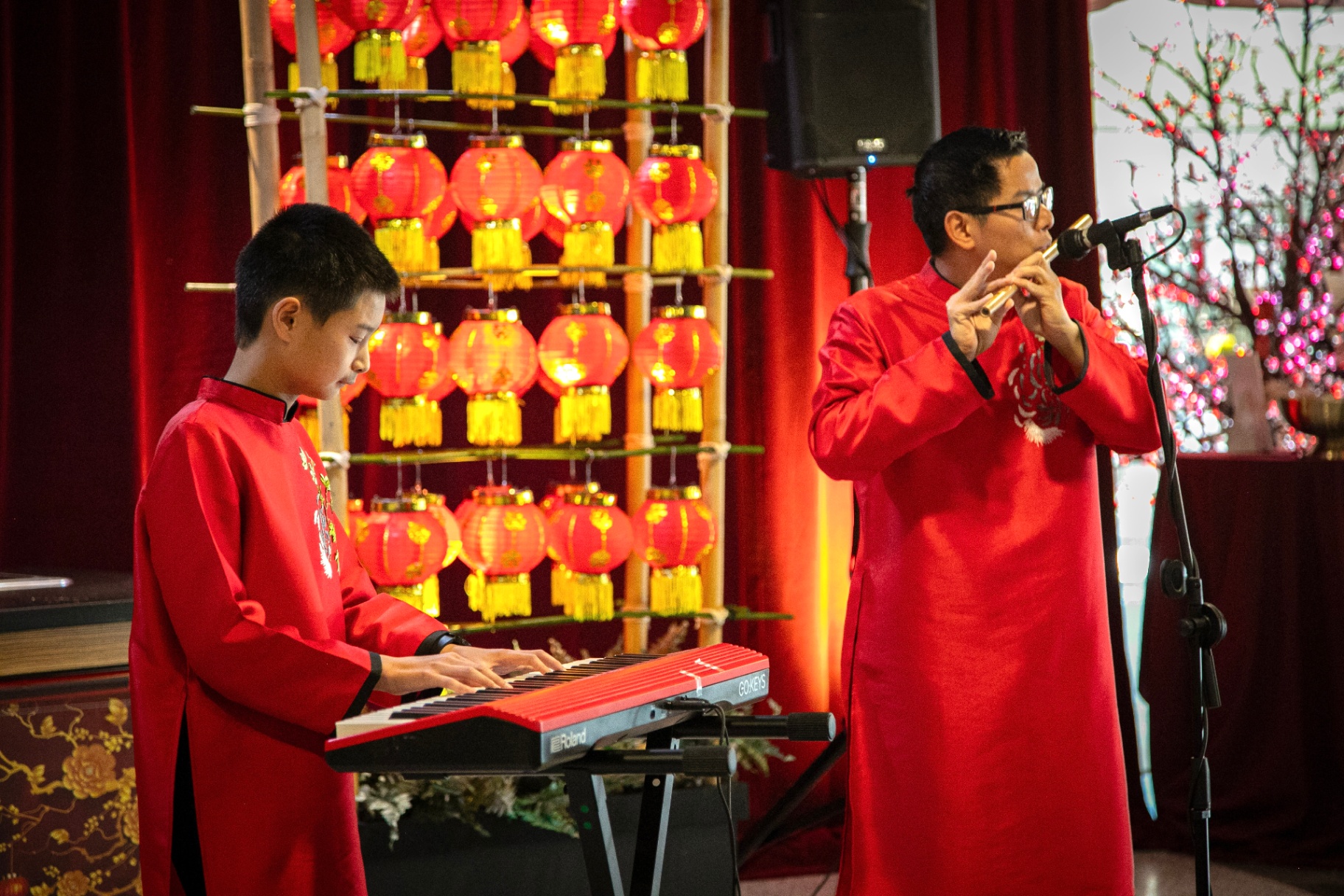 Phu & Peter Le performing in traditional red attire with Chinese lanterns in the background